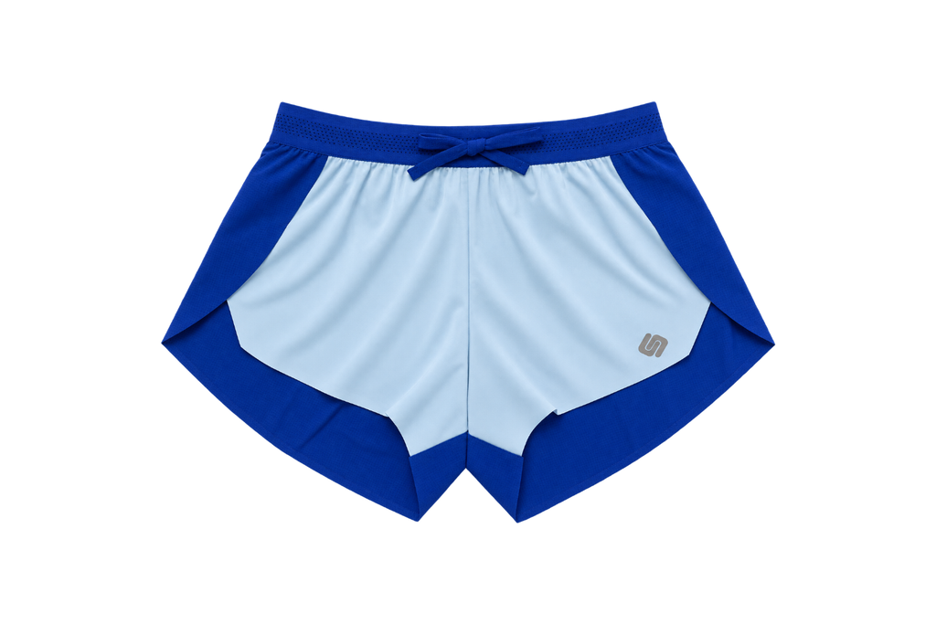 A pair of athletic shorts in a colorblock design of royal blue and light blue, featuring a drawstring waistband and a small metallic logo on the lower left leg, shown against a plain white background.